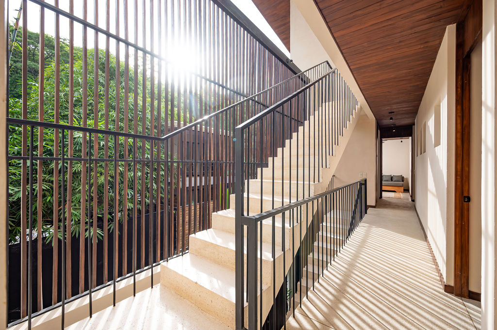 Stone stair and black steel railing rising past a slatted timber screen