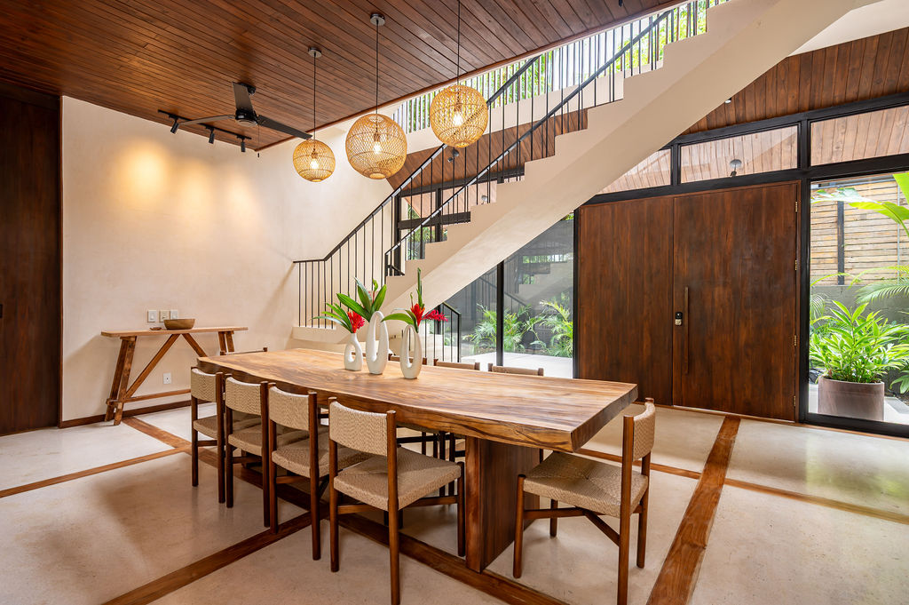 The dining table with the teak staircase and entry doors behind